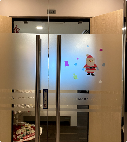 Frosted glass entrance door with Santa decoration at Netmore office, symbolizing a welcoming and festive workplace environment.