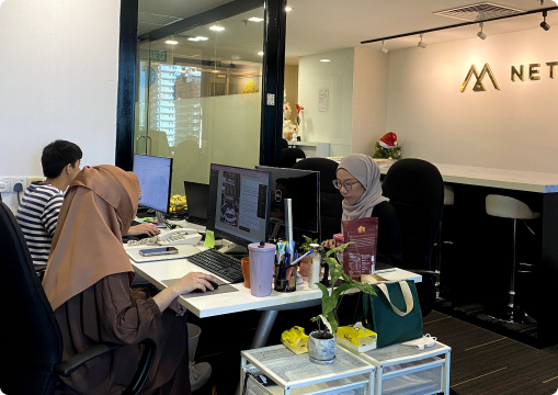 Netmore creative team collaborating at office desks, showing a dynamic and friendly career environment in Malaysia.